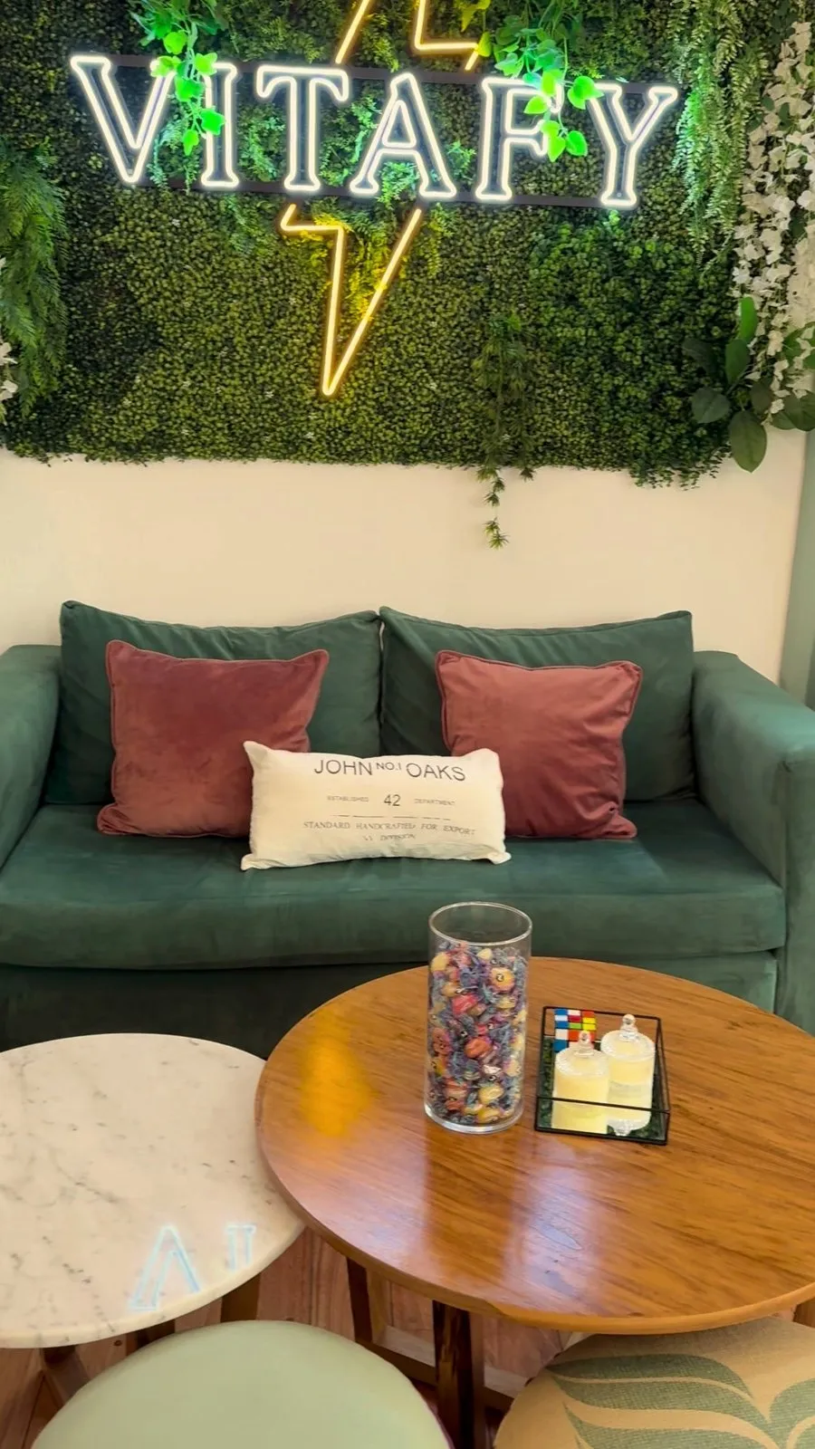 Recepción de Vitafy con sillones verdes y el cartel de neón